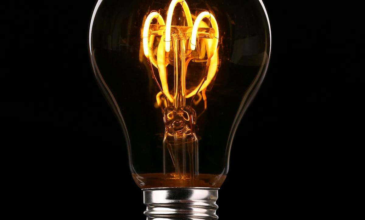 Close-up of an illuminated Edison-style light bulb on a dark background.