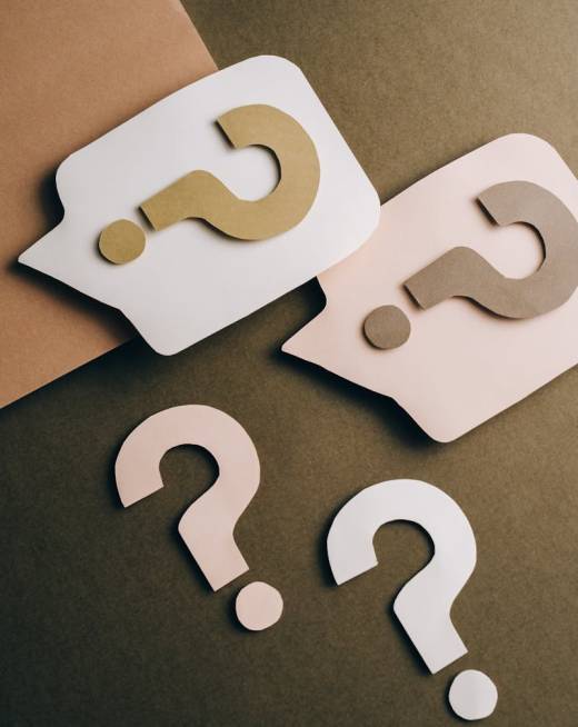 Photo by Leeloo The First Artistic paper cutouts of question marks creating a conceptual design on a brown surface.